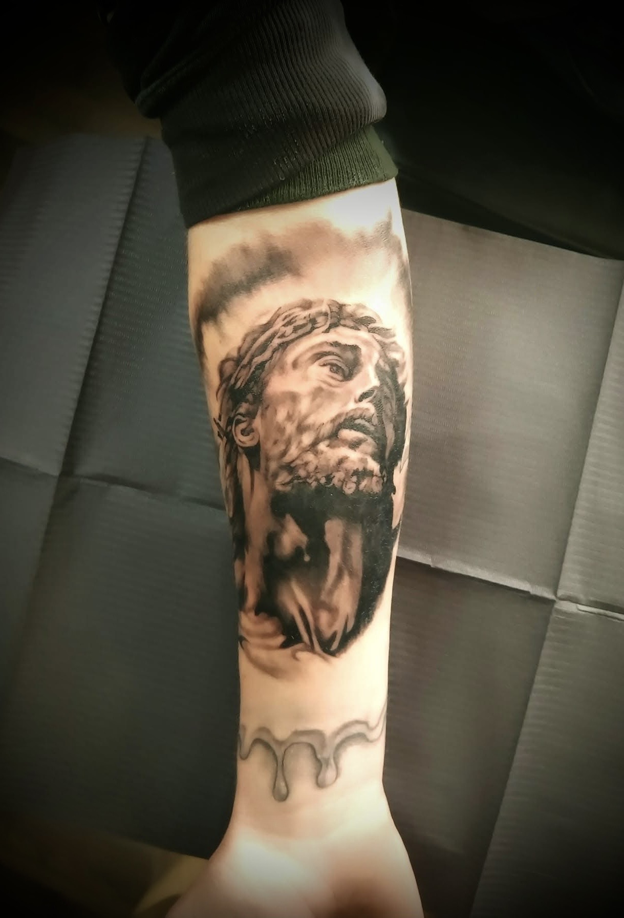 Black and gray Jesus portrait forearm tattoo by Michael, the featured piece of the Black & Gray collection